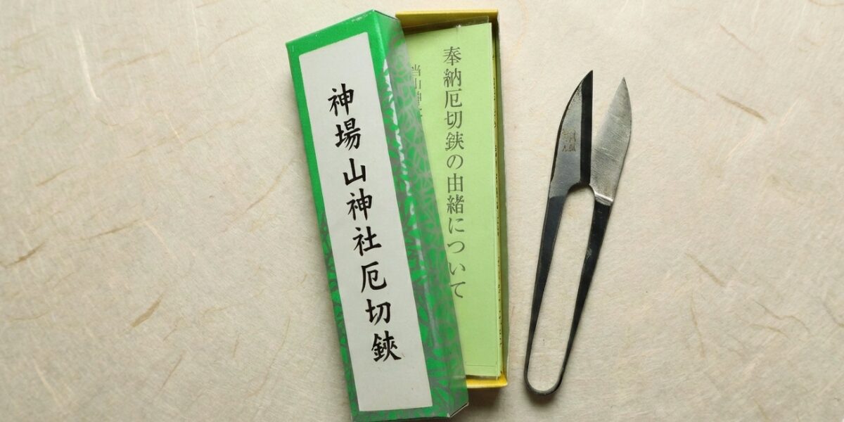 神場山神社厄切鋏と書かれた緑色の箱と、奉納厄切鋏の由緒についてと書かれた紙、そして黒い和鋏(握り鋏)