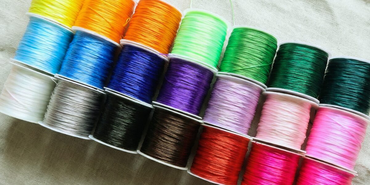 生成り色の布の上に並べられた、全21色の推し活天然石ブレスレット用オペロンゴム